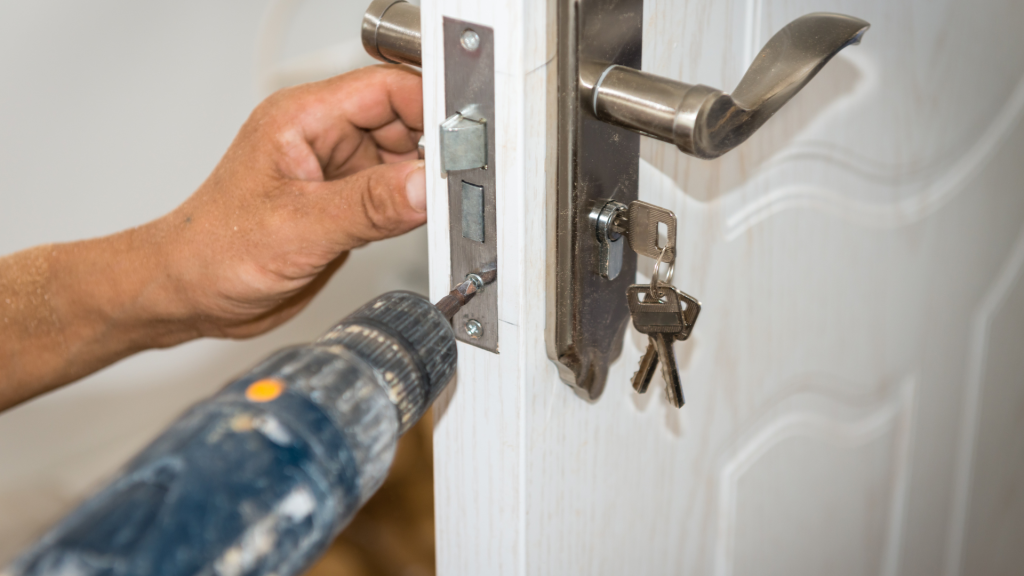 A locksmith using a screwdriver to fix a door handle.